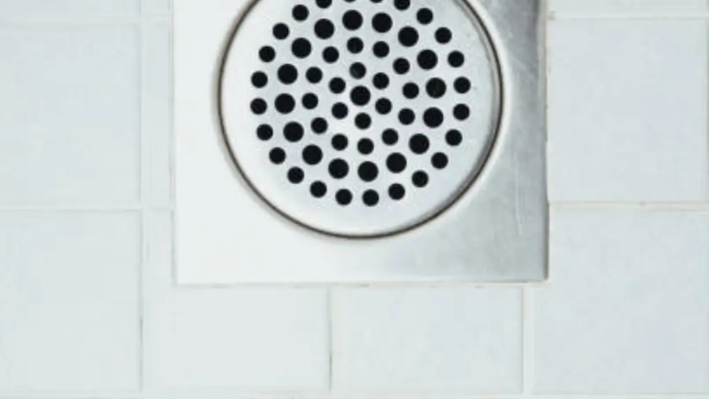 Ralo de banheiro limpo com tampa metálica sobre piso de cerâmica branca, representando solução para mau cheiro no ralo do banheiro.
